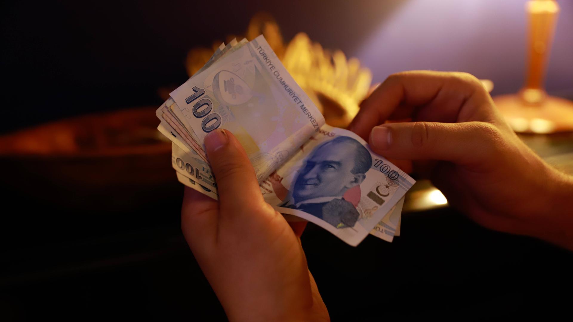 Eine Hand hält Geldscheine in türkischer Währung Lira einem Café in Izmir in der Türkei.