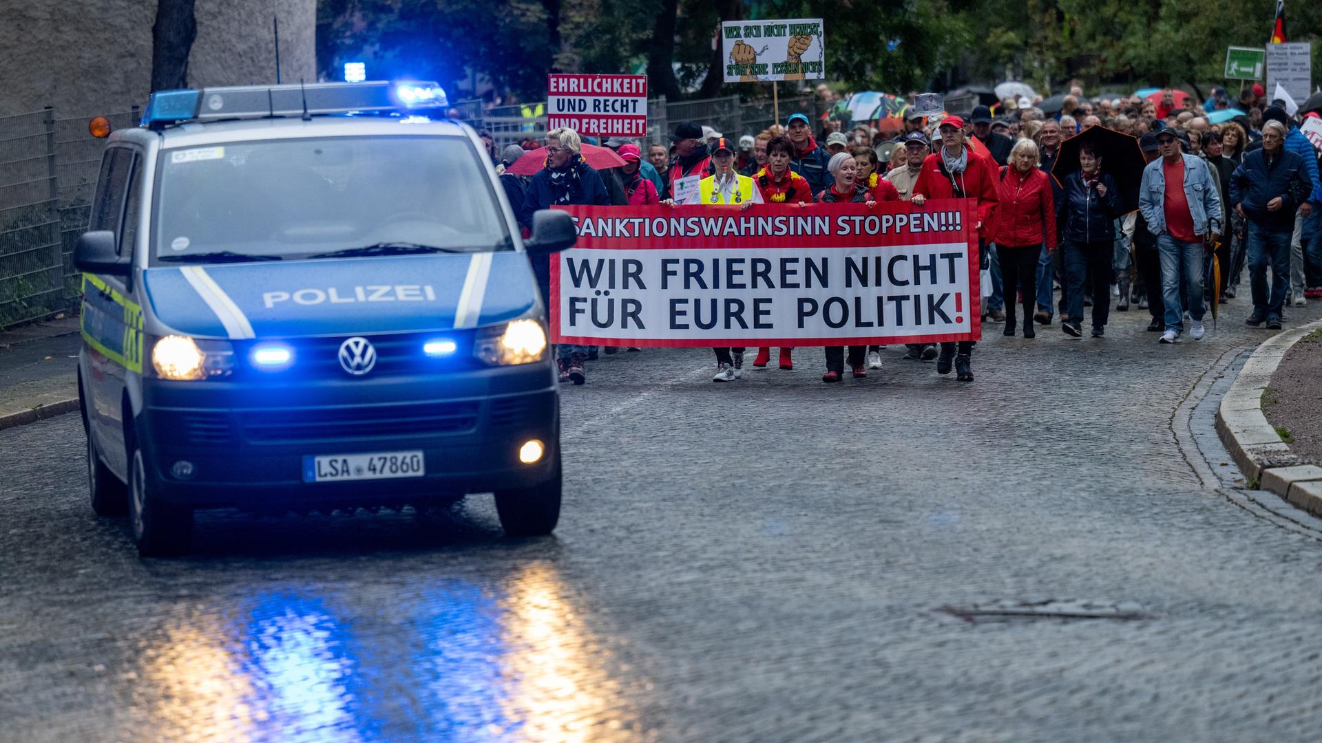 Teilnehmer einer Demonstration des Bündnisses "Bewegung Halle" ziehen durch Halle/Saale. Am Kopf der Demonstration tragen die Teilnehmer ein Banner mit der Aufschrift "Sanktionswahnsinn stoppen! Wir frieren nicht für eure Politik!" Teilnehmer einer Demonstration des Bündnisses "Bewegung Halle" ziehen durch Halle/Saale. Am Kopf der Demonstration tragen die Teilnehmer ein Banner mit der Aufschrift "Sanktionswahnsinn stoppen! Wir frieren nicht für eure Politik!"