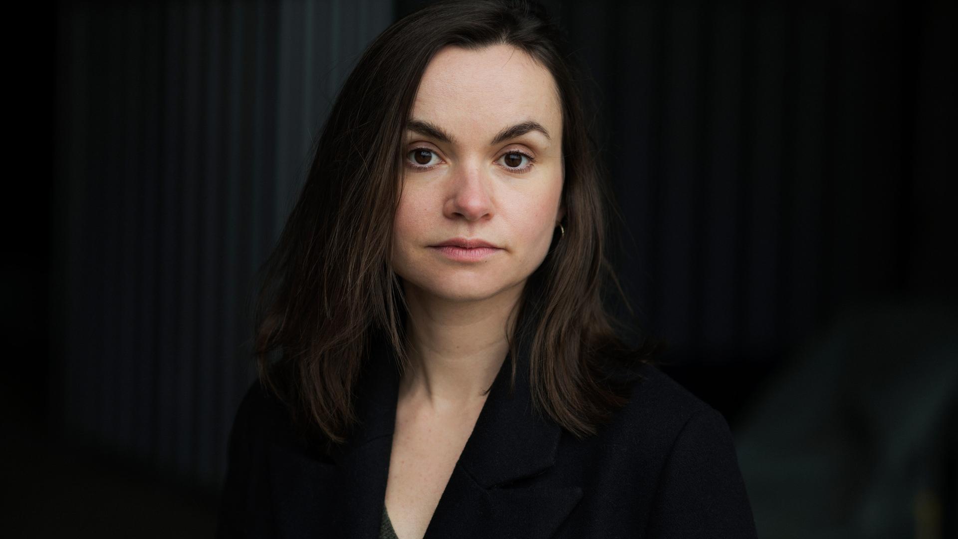 Die Schriftstellerin Franziska Gänsler steht vor einem schwarzen Hintergrund und blickt ernst in die Kamera. Die Schriftstellerin Franziska Gänsler steht vor einem schwarzen Hintergrund und blickt ernst in die Kamera.