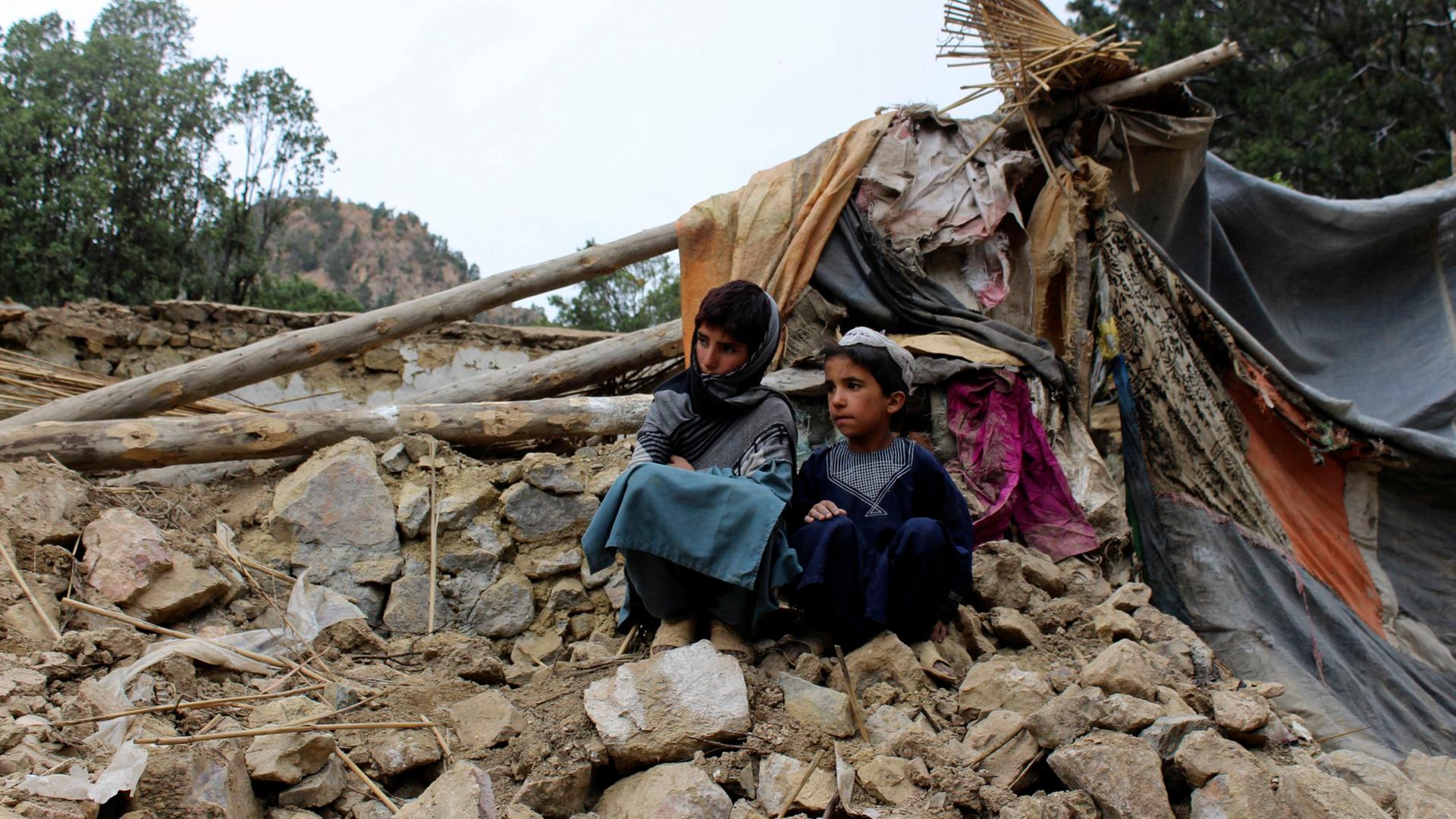 Afghanistan, Khost: Zwei Jungen sitzen in der Nähe ihres Hauses, das bei einem Erbeben zerstört wurde. Bei einem schweren Erdbeben in der afghanisch-pakistanischen Grenzregion ist die Zahl der Verletzten und Todesopfer weiter gestiegen. 
