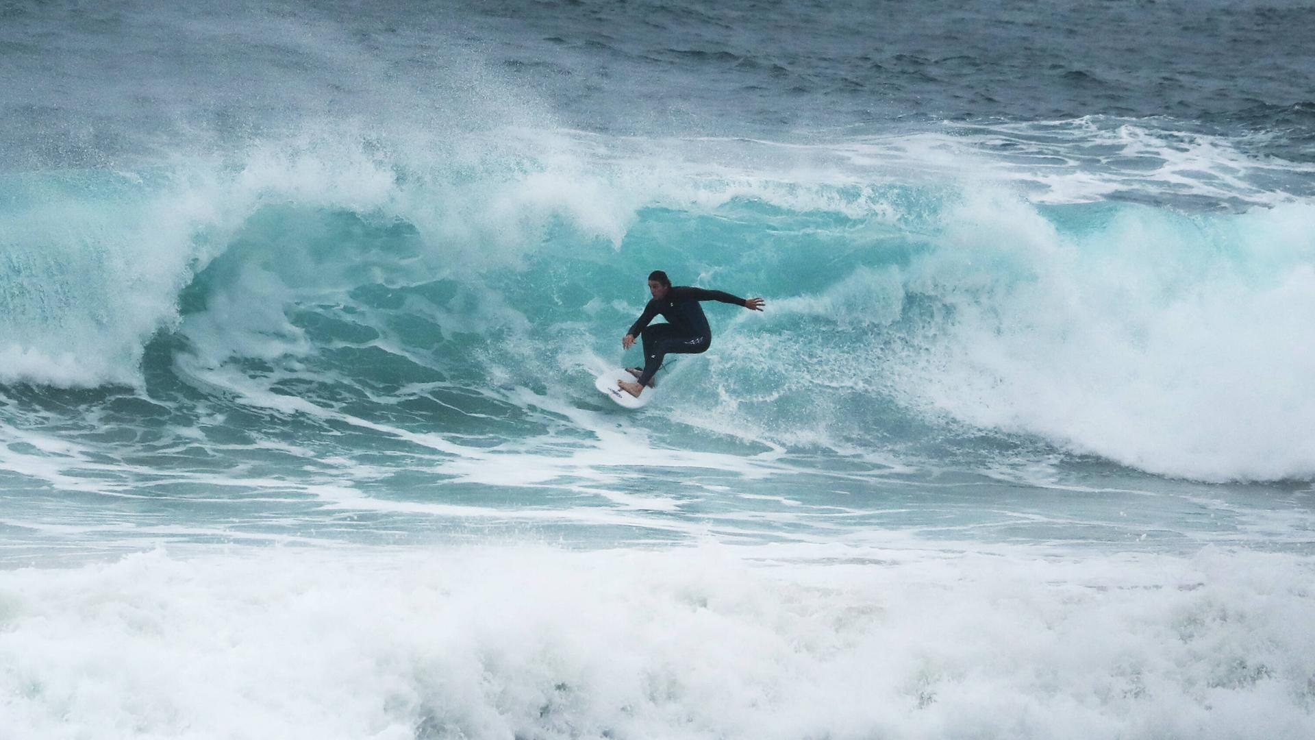 Auf dem Bild ist ein Surfer zu sehen, der über eine Welle reitet. Auf dem Bild ist ein Surfer zu sehen, der über eine Welle reitet.