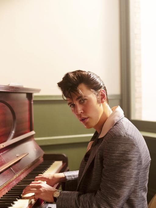 Filmstill aus "Elvis" von Baz Luhrmann. Der Schauspieler Austin Butler sitzt als Elvis am Klavier, 2022.