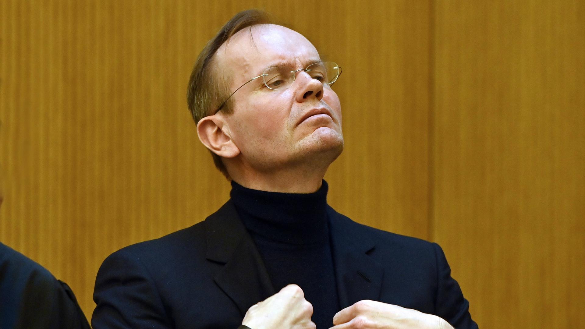 Markus Braun steht in einem schwarzen Anzug im Gerichtssaal und zupft sein Sakko zurecht. Markus Braun steht in einem schwarzen Anzug im Gerichtssaal und zupft sein Sakko zurecht.