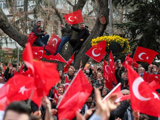 Wahlkampfveranstaltung der Opposition in der Türkei - es werden türkische Fahnen geschwenkt, drei Männer sind auf einen Baum geklettert.