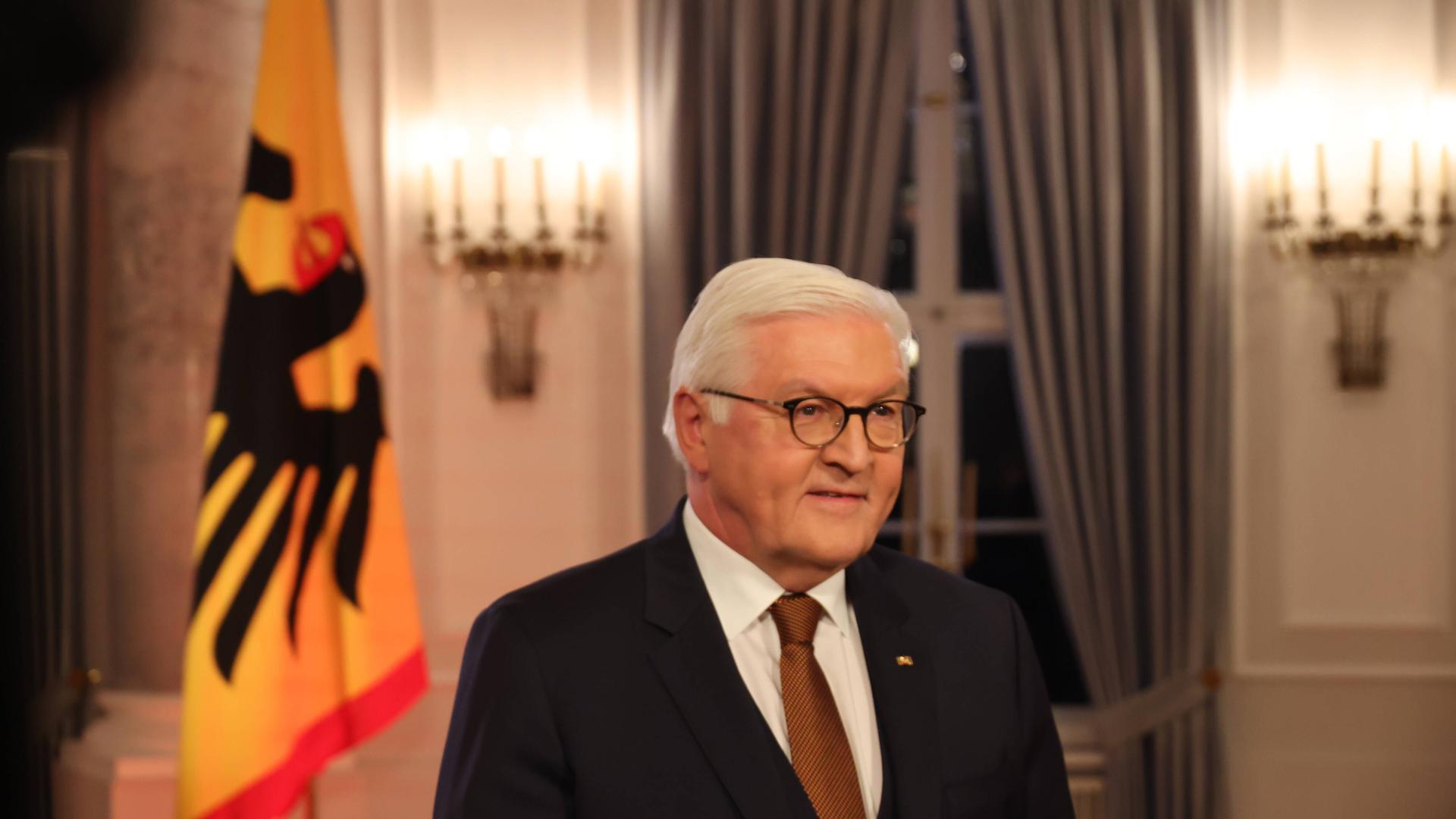 Bundes-Präsident Frank-Walter Steinmeier steht neben einer Deutschlandflagge im Schluss Bellevue. Bundes-Präsident Frank-Walter Steinmeier steht neben einer Deutschlandflagge im Schluss Bellevue.