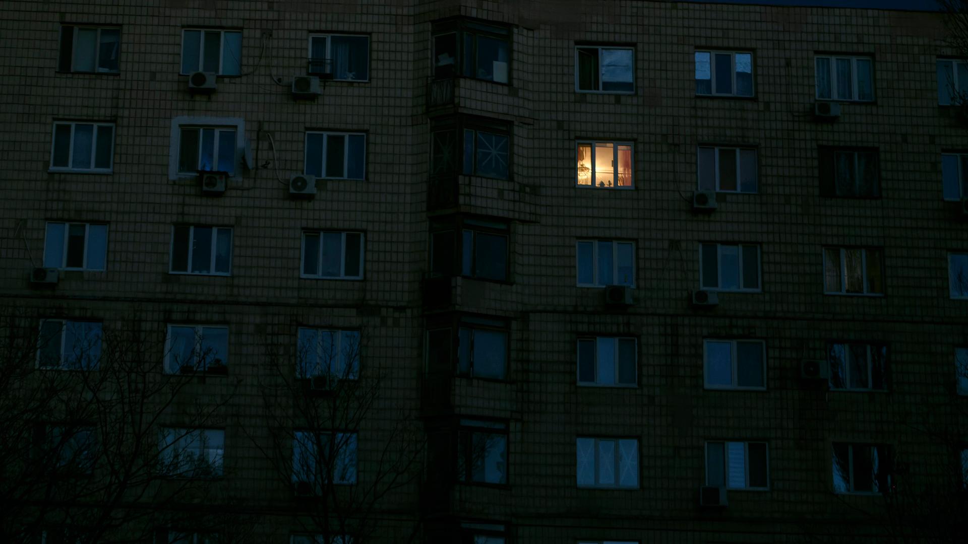 In einem dunklen Mehrfamilienhaus brennt das Licht in einem Zimmer. In einem dunklen Mehrfamilienhaus brennt das Licht in einem Zimmer.