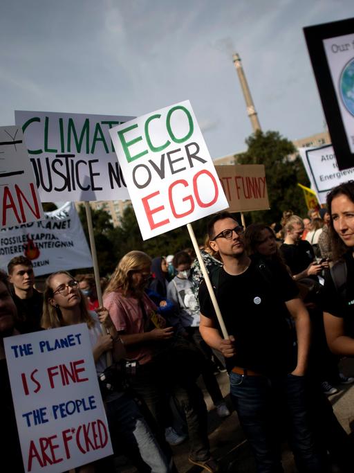 Auf einer Klima-Demonstration hält ein Mann ein kleines Plakat hoch, auf dem steht: Eco statt Ego