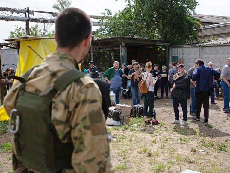 Zu sehen sind ein Mann in Militärkleidung und Zivilisten bei einer Evakuierungsaktion auf dem Gelände des Chemiewerks Azot in Sjewjerodonezk im Osten der Ukraine.