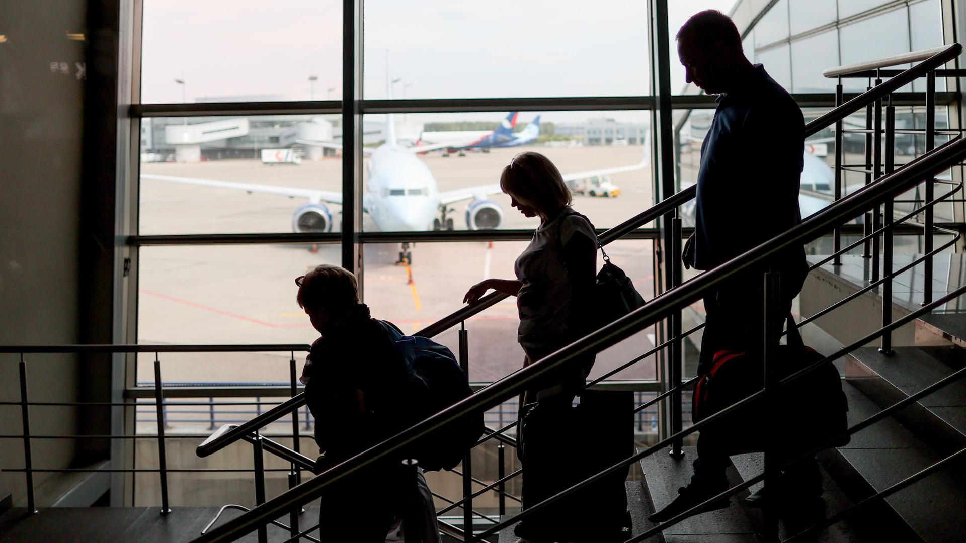 Reisende gehen an Moskaus ältestem Flughafen Vnukovo eine Treppe herunter Reisende gehen an Moskaus ältestem Flughafen Vnukovo eine Treppe herunter