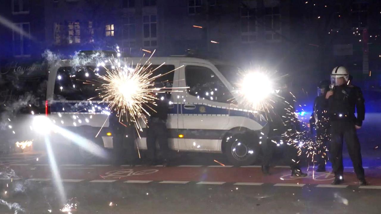 Polizeibeamte stehen in der Silvesternacht in Berlin hinter explodierendem Feuerwerk. Polizeibeamte stehen in der Silvesternacht in Berlin hinter explodierendem Feuerwerk.