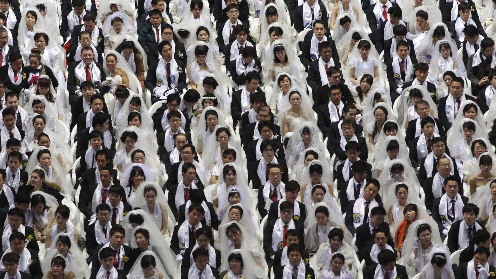 Paare stehen bei einer Massenhochzeit der Moon-Sekte. Die Frauen sind weiß gekleidet, die Männer schwarz (Aufnahme aus dem Jahr 2013)