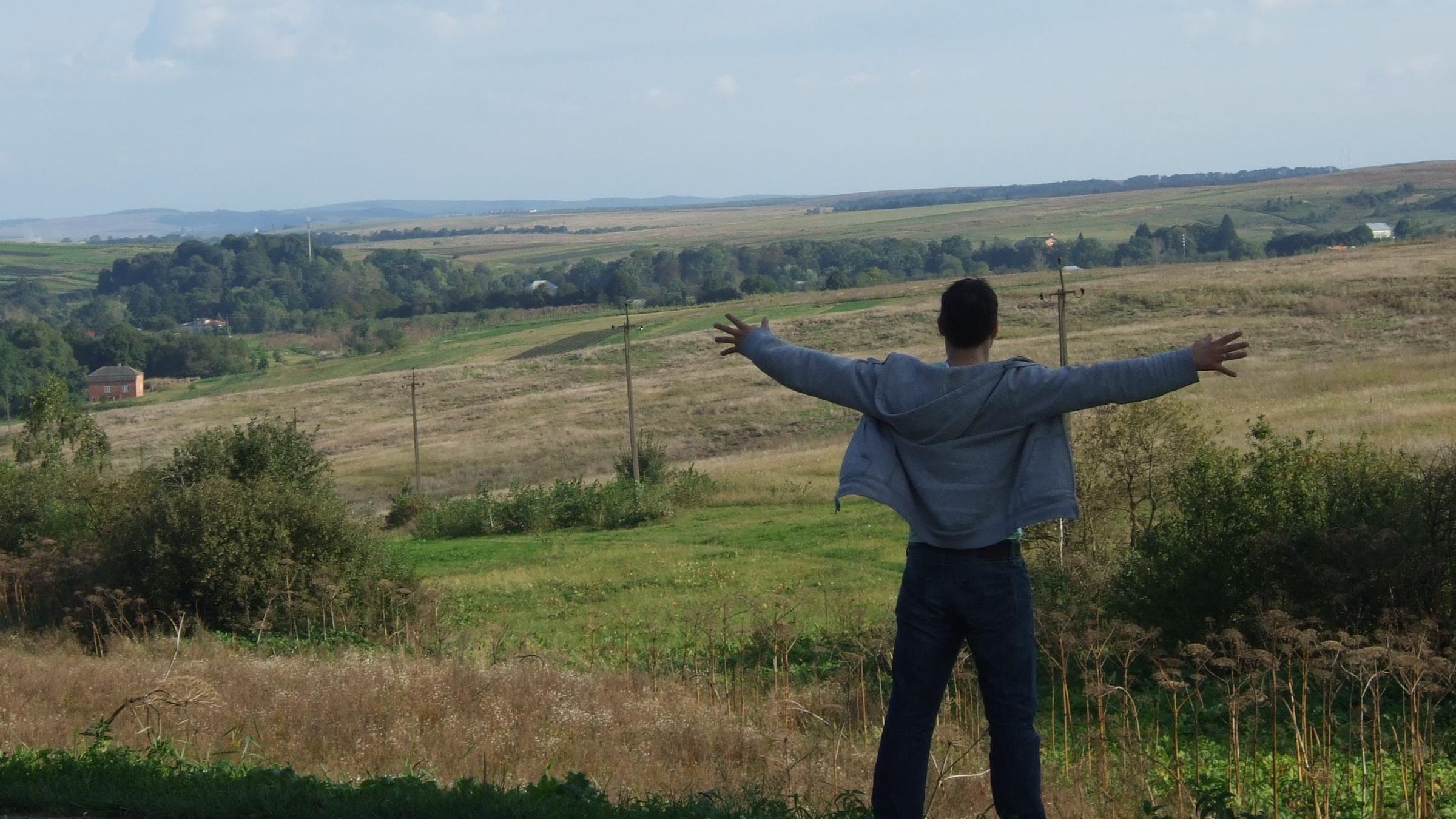 Der Autor steht vor ukrainischer Landschaft.