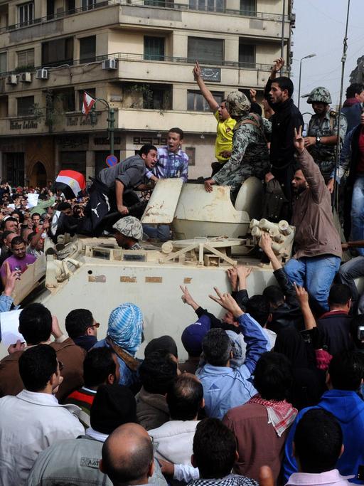 Demonstranten protestieren in Kairo auf dem Tahrir-Platz neben einem Panzer am 29.01.2011.
