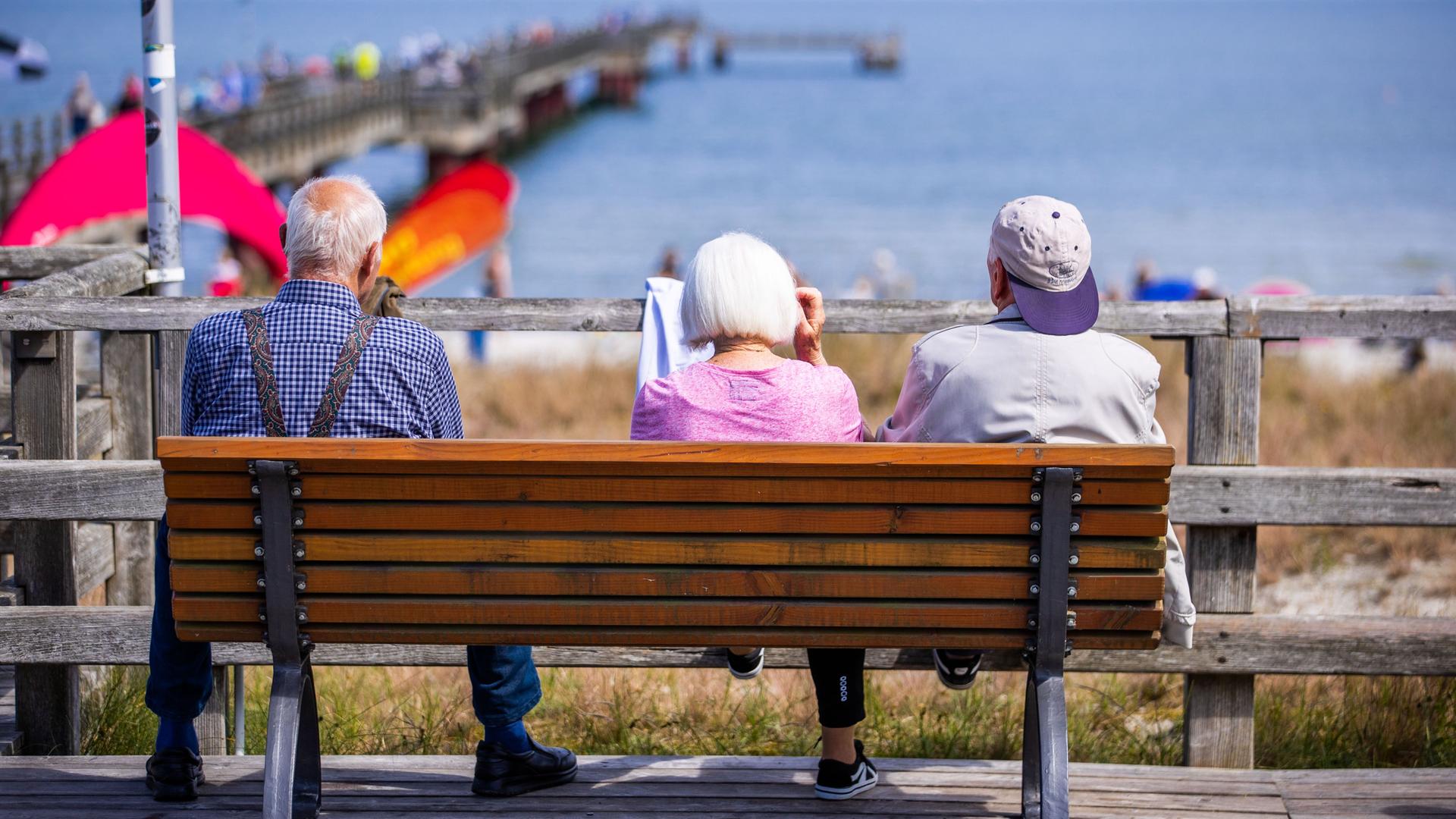 Drei Senioren sitzen auf einer Bank an der Seebrücke Drei Senioren sitzen auf einer Bank an der Seebrücke