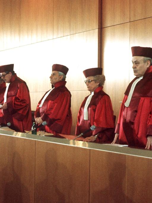 Richter und Richterin vom Bundesverfassungsgericht in roten Roben am Richtertisch