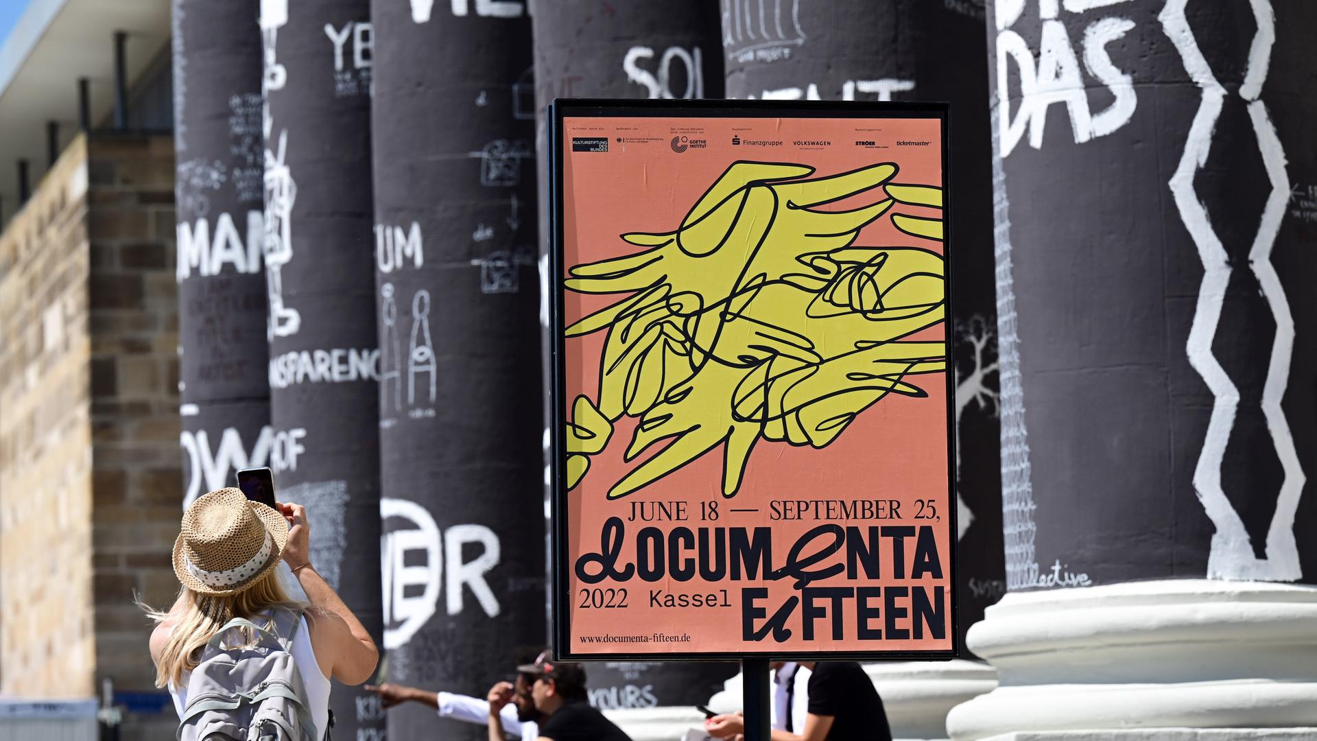 Eine Frau fotografiert die von Dan Perejovschi bemalten Säulen des Fridericianums auf der Documenta in Kassel. Eine Frau fotografiert die von Dan Perejovschi bemalten Säulen des Fridericianums auf der Documenta in Kassel.