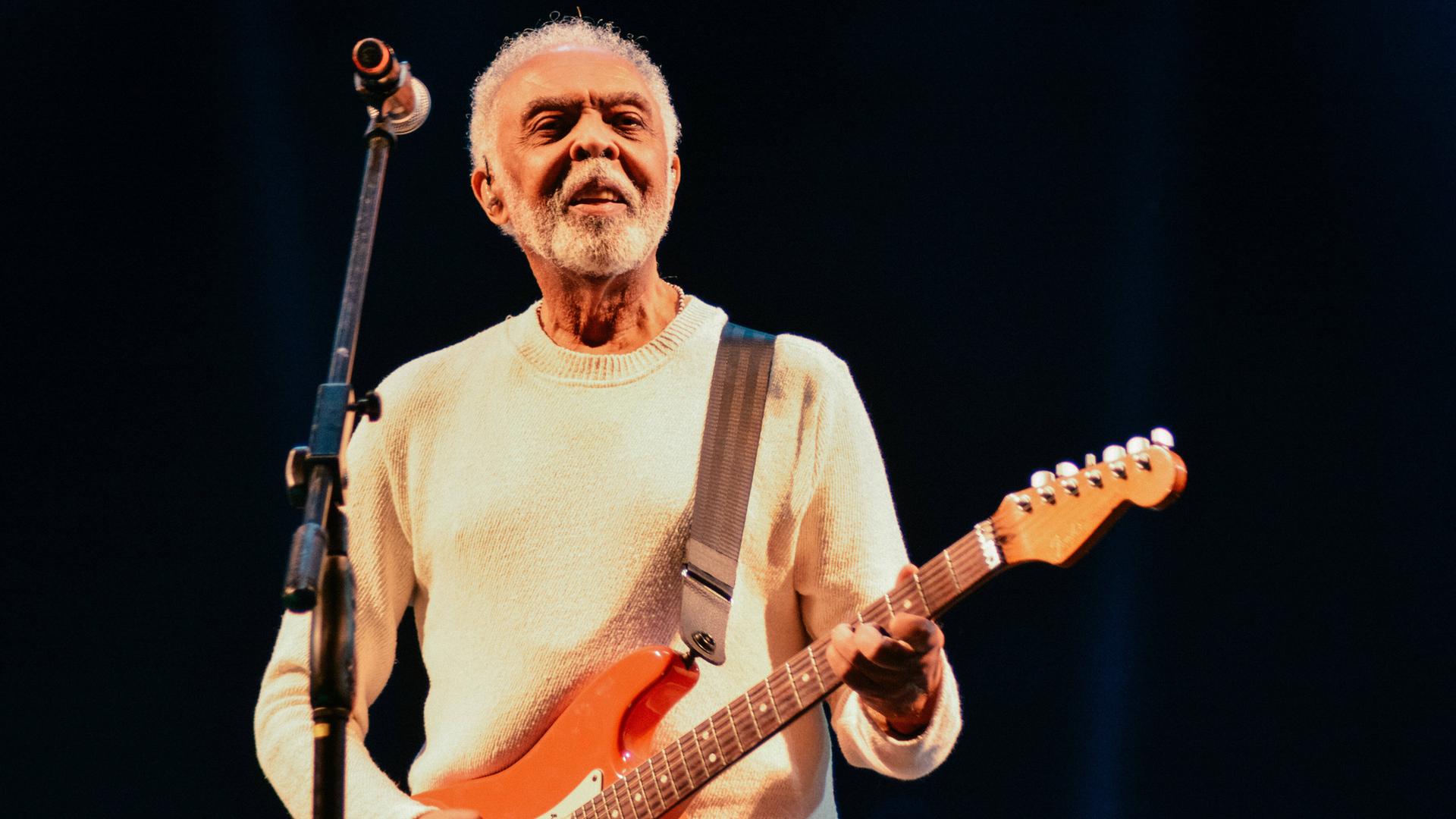 Auf dem Bild ist ein älterer Herr mit Gitarre zu sehen. Es ist der Musiker Gilberto Gil. Auf dem Bild ist ein älterer Herr mit Gitarre zu sehen. Es ist der Musiker Gilberto Gil.