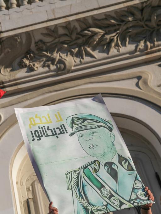 Eine Karikatur des tunesischen Präsidenten Kais Saied in Militäruniform mit der arabischen Aufschrift "Nein zur Herrschaft eines Diktators" neben der tunesischen Flagge. Während einer Demonstration von Anhängern tunesischer Oppositionsparteien und tunesischer zivilgesellschaftlicher Gruppen in Tunis am 22. Juli 2022, um gegen den tunesischen Präsidenten Kais Saied zu protestieren und zum Boykott des bevorstehenden Verfassungsreferendums am 25. Juli aufzurufen. 