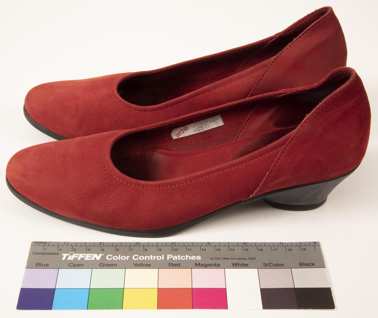 Ein rotes Paar Frauen-Schuhe steht vor einer Farbskala Ein rotes Paar Frauen-Schuhe steht vor einer Farbskala