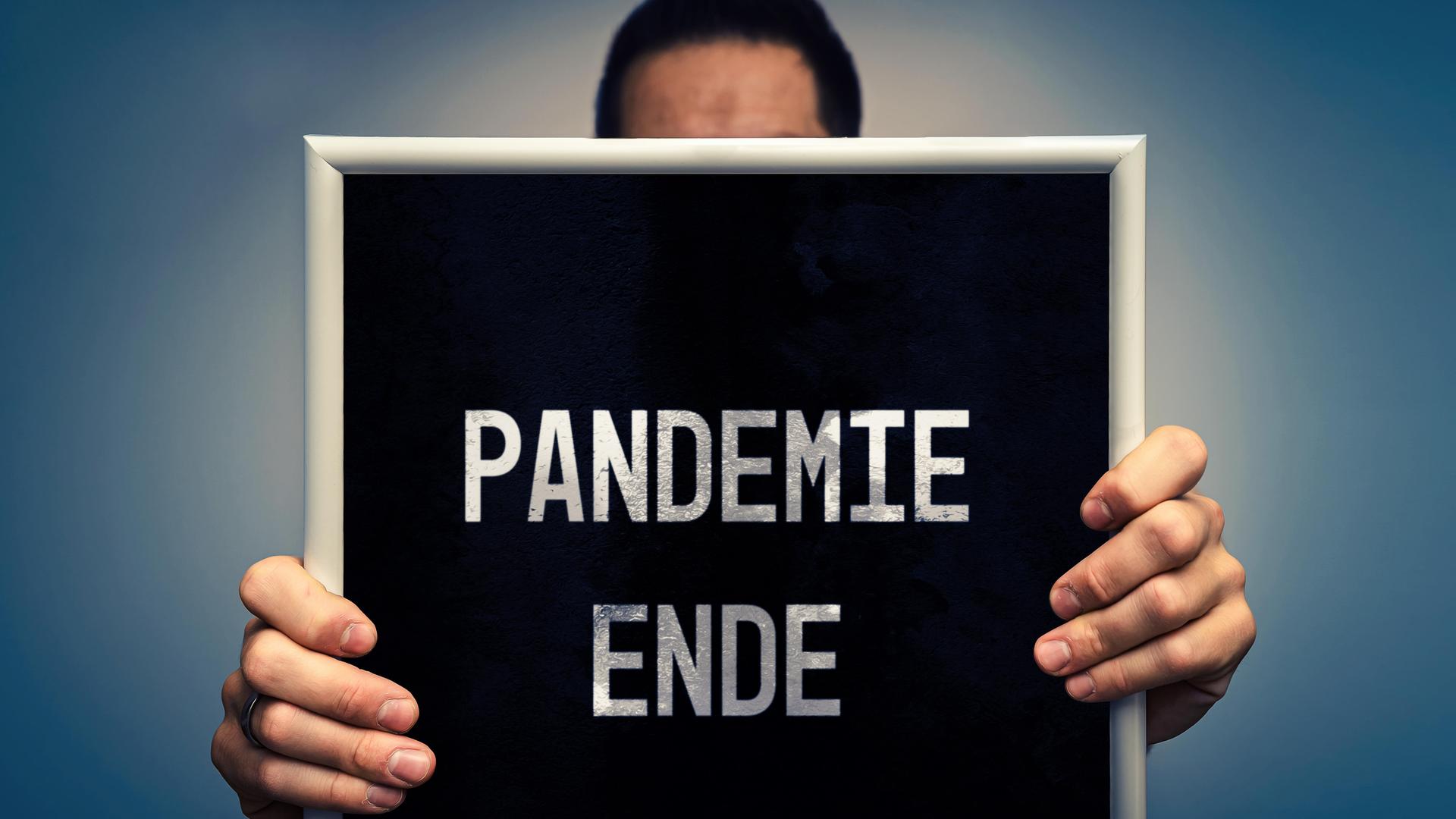 Ein Mann hält ein Schild mit der Aufschrift "Pandemie Ende". Ein Mann hält ein Schild mit der Aufschrift "Pandemie Ende".