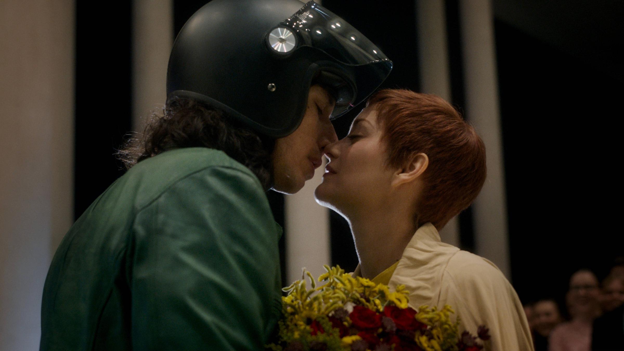Ein Mann mit Motorradhelm küsst eine Frau, die einen Blumenstrauß hält....</p>

                        <a href=