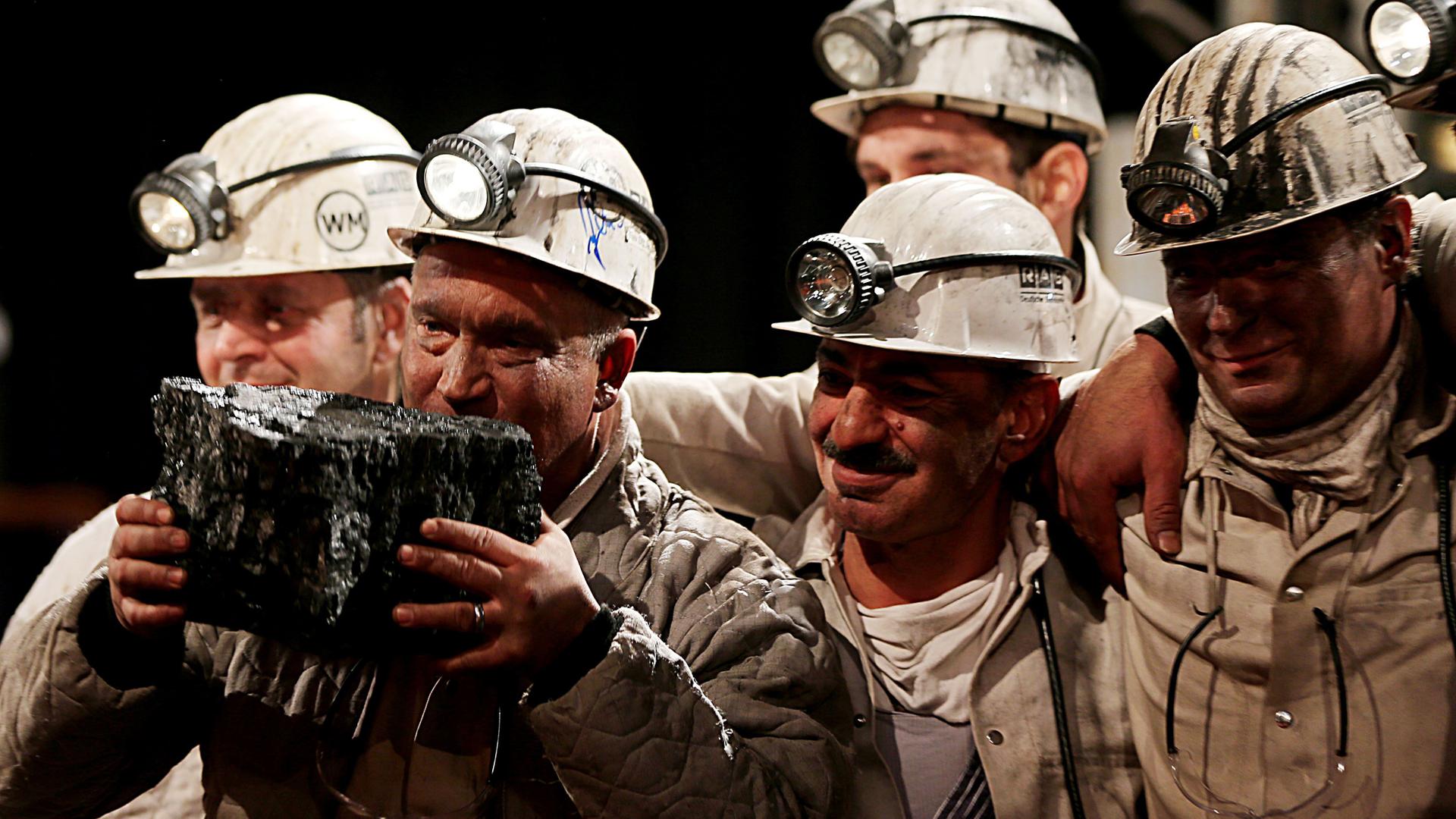 Fünf Bergmänner mit dem letzten Stück in Deutschland abgebauter Steinkohle.