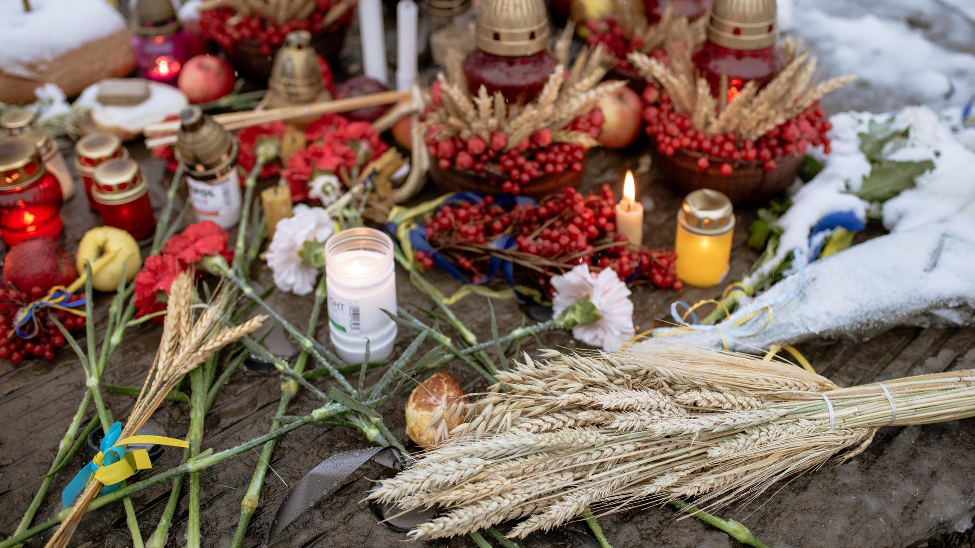 Das Bild zeigt Kerzen, Weizen und Blumen am Holodomor-Denkmal in der Ukraine