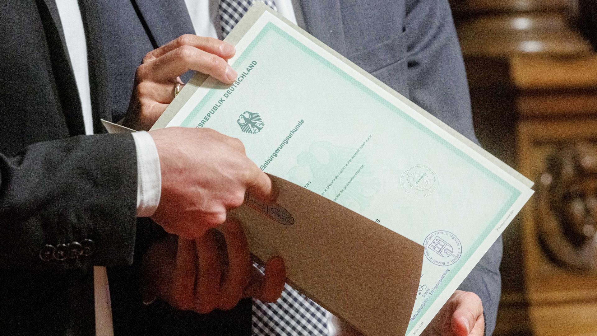 Eine Einbürgerungsurkunde der Bundesrepublik Deutschland wird bei einem Festakt im Hamburger Rathaus an eine Person übergeben stammt.
