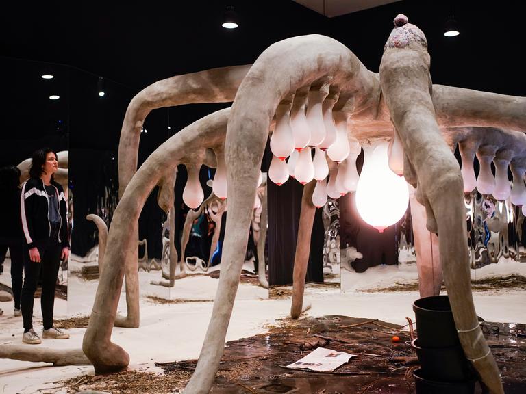 Eine Frau steht in der Kunsthalle Mannheim in der Ausstellung "1,5 Grad. Verflechtungen von Leben, Kosmos, Technik" vor dem Kunstwerk "Moother" von Laure Prouvost.  