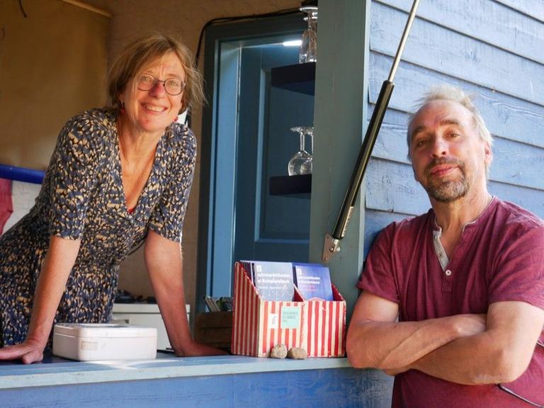 Eine Frau und ein Mann stehen an einem zur Theaterkasse hergerichteten blauen Bauwagen. Eine Frau und ein Mann stehen an einem zur Theaterkasse hergerichteten blauen Bauwagen.