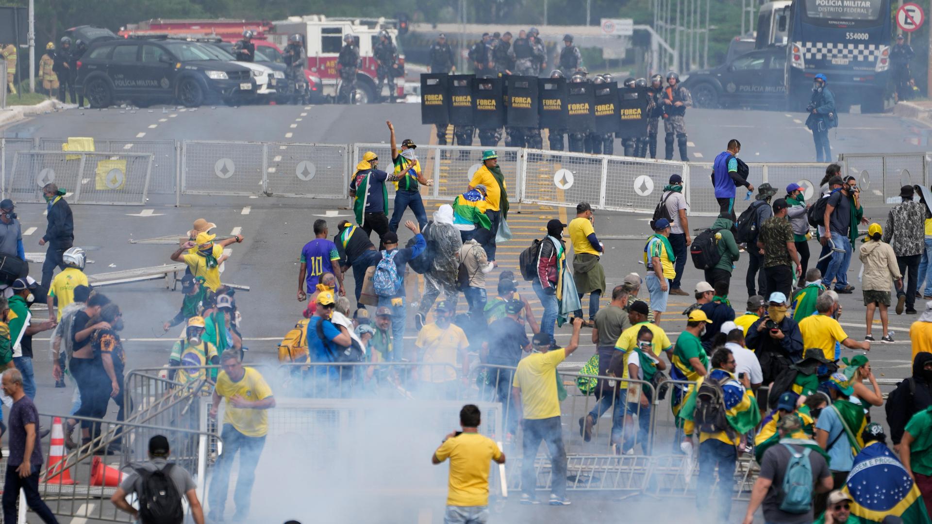 Bolsonaro-Anhänger vor einer Polizei-Barrikade inmitten von Tränengas-Schwaden.