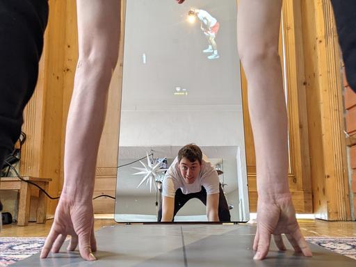 Ein Mann macht Fitness vor einem Fitness-Spiegel.