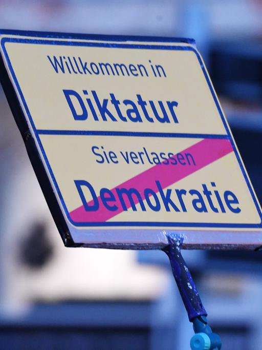 Auf einem Schild bei einer Demonstration der Querdenken-Bewegung steht "Willkommen in der Diktatur - Sie verlassen Demokratie".